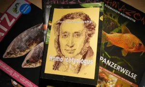 Okładka książki "Homo ichtyologus" z portretem Jana Burzanovsky'ego, obok magazyny o akwarystyce z rybami.