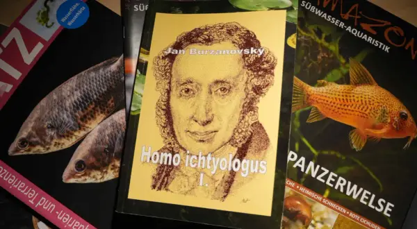 Okładka książki "Homo ichtyologus" z portretem Jana Burzanovsky'ego, obok magazyny o akwarystyce z rybami.